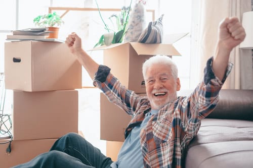 happy-senior-man-sitting-floor-relaxing-new-home-living-room-with-cardboard-boxes